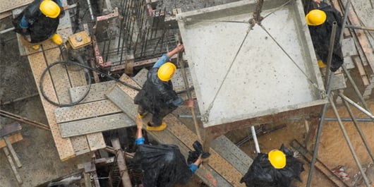 4 workers with hardhats, pouring cement in the rain_600x300_blog